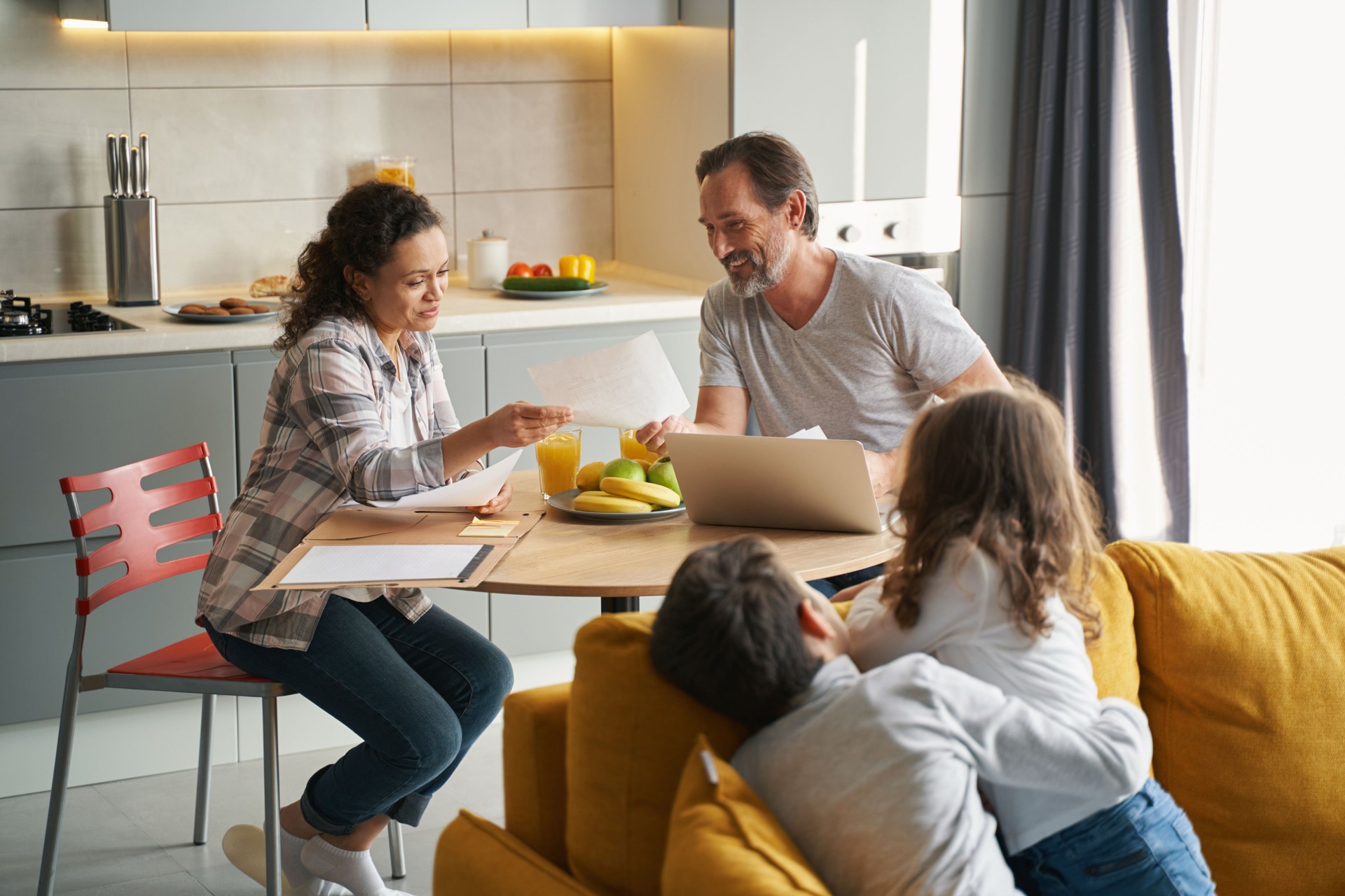 Parents doing taxes in kitchen while children looking